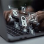 imagem de Cybersecurity: mãos digitando ao notebook com ícones de segurança projetados sobre o teclado